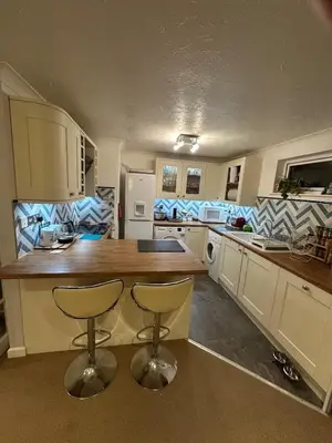 a kitchen with a counter and two bar stools at Penolva Beach Side Apartment in Perranporth
