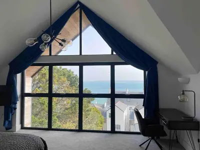 a bedroom with a large window with blue curtains at Perpetual House St Ives Cornwall in St Ives