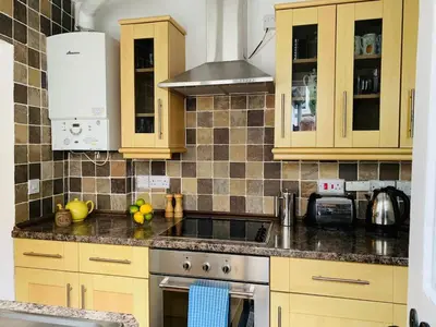 a kitchen with wooden cabinets and a stove top oven at Maypole Cottages - No 12 Broad Street in Padstow