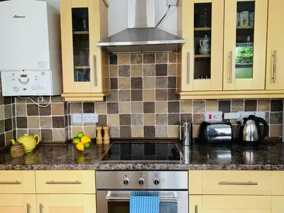 a kitchen with wooden cabinets and a stove top oven at Maypole Cottages - No 12 Broad Street in Padstow