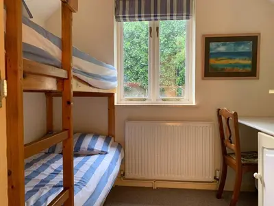 a bedroom with two bunk beds and a desk at Maypole Cottages -5 Mill Road in Padstow