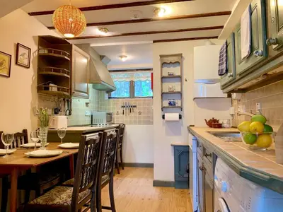 a kitchen with a table with chairs and a counter top at Maypole Cottages -5 Mill Road in Padstow