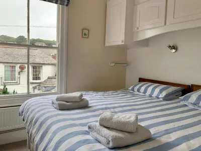a bedroom with a blue and white bed with towels on it at Maypole Cottages -5 Mill Road in Padstow
