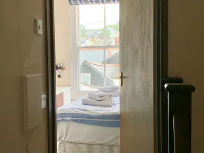 a bedroom with a bed and a window with towels at Maypole Cottages -5 Mill Road in Padstow