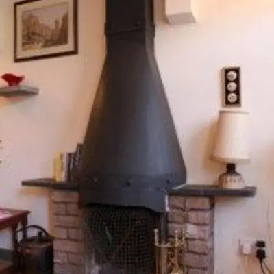 a fireplace with a black stove in a living room at Maypole Cottages -5 Mill Road in Padstow