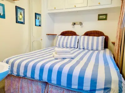 a blue and white striped bed with towels on it at - Maypole Cottages - No 2 Mill Road in Padstow
