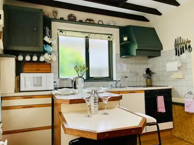 a kitchen with green cabinets and a table with glasses on it at - Maypole Cottages - No 2 Mill Road in Padstow