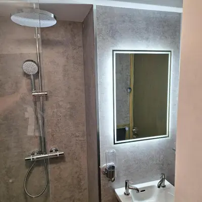 a bathroom with a shower with a sink and a mirror at - Maypole Cottages - No 2 Mill Road in Padstow