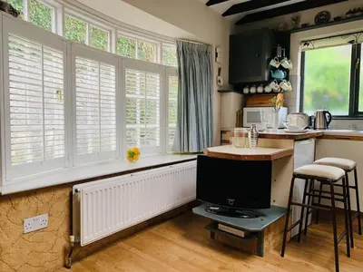 a kitchen with a counter with a tv and some windows at - Maypole Cottages - No 2 Mill Road in Padstow