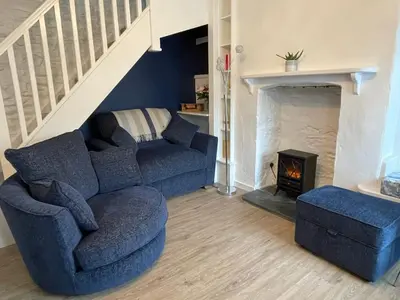 a living room with a blue couch and a fireplace at Cosy Cottage, Mevagissey in Mevagissey