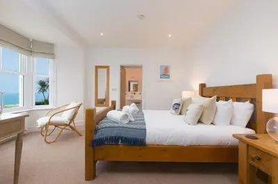 a bedroom with a bed with white sheets and pillows at Heatherleigh in Carbis Bay