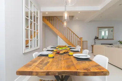 a dining room with a wooden table and white chairs at Heatherleigh in Carbis Bay