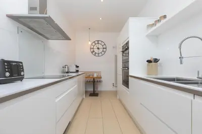 a white kitchen with white cabinets and a sink at Heatherleigh in Carbis Bay