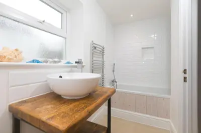 a bathroom with a white bowl sink on a wooden table at Heatherleigh in Carbis Bay