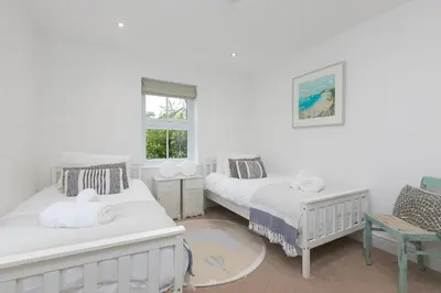 a bedroom with two beds and a chair at Heatherleigh in Carbis Bay
