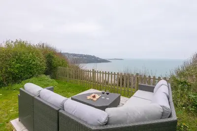 a outdoor couch with a table and a view of the ocean at Heatherleigh in Carbis Bay