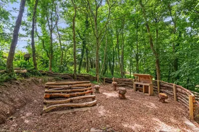 a group of logs and a fence in the woods at House 17 in Looe