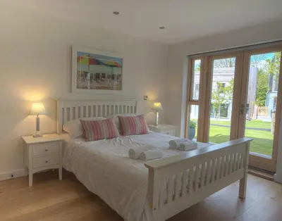 a bedroom with a large white bed with two lamps at House 17 in Looe