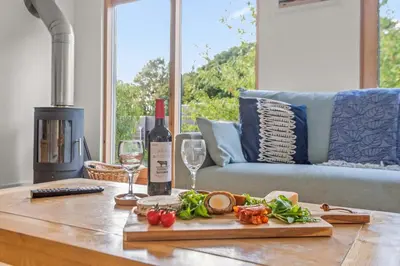 a table with a cutting board with a bottle of wine and wine glasses at House 17 in Looe