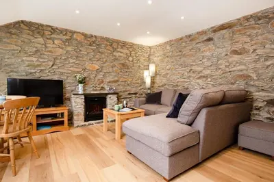 a living room with a stone wall at Beautiful Cottage nr Perranporth Private Parking in Perranzabuloe