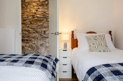 two beds in a bedroom with a stone wall at Beautiful Cottage nr Perranporth Private Parking in Perranzabuloe