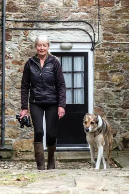 a woman walking a dog in front of a building at Levalsa House in Pentewan