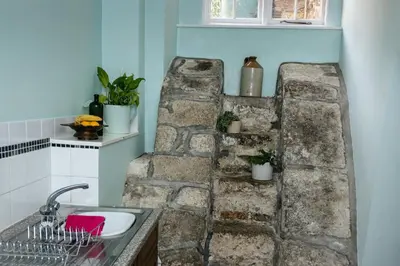 a bathroom with a stone wall next to a sink at Levalsa House in Pentewan