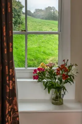 a window with a vase of flowers on a window sill at Levalsa House in Pentewan
