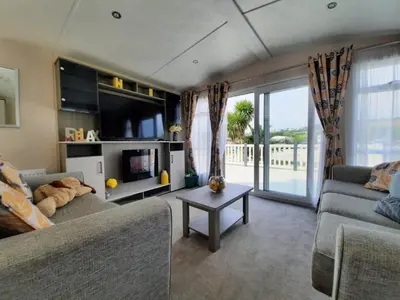 a living room with a couch and a tv at Sunset retreat lodge with large wrap around decking in Newquay