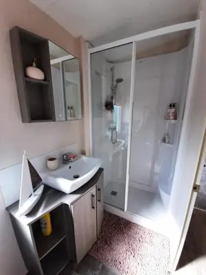 a bathroom with a white sink and a shower at Sunset retreat lodge with large wrap around decking in Newquay