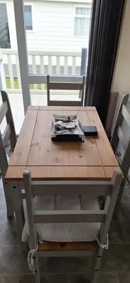 a wooden table with chairs and a newspaper on it at Sunset retreat lodge with large wrap around decking in Newquay