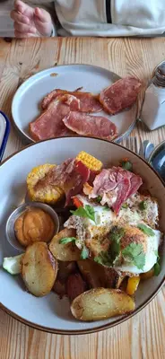 a plate of food with meat and potatoes on a table at Sunset retreat lodge with large wrap around decking in Newquay