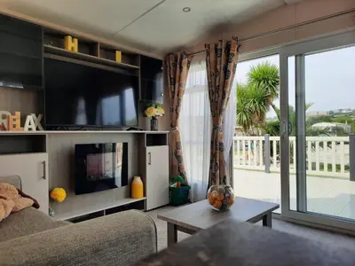 a living room with a couch and a large window at Sunset retreat lodge with large wrap around decking in Newquay