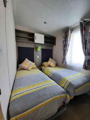 two beds in a small room with a window at Sunset retreat lodge with large wrap around decking in Newquay