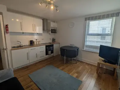 a kitchen with white cabinets and a table in a room at Bijou in St Ives