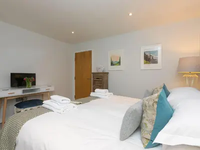 two beds in a bedroom with a desk and a tv at Wingspan in St Ives