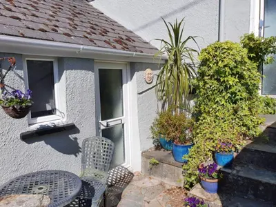 a table and chairs in front of a house with plants at SeaView-PetsOK-Patio-1BR in Mevagissey