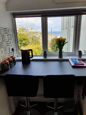 a table with two chairs and a window with a view at SeaView-PetsOK-Patio-1BR in Mevagissey