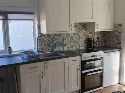 a kitchen with white cabinets and a sink at SeaView-PetsOK-Patio-1BR in Mevagissey