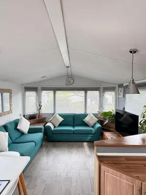 a living room with a blue couch and a tv at Stylish Family Friendly 3-Bed Caravan Escape at Seven Bays Park in St Merryn