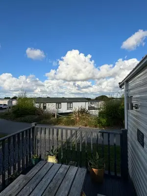 a wooden bench sitting on a porch next to a house at Stylish Family Friendly 3-Bed Caravan Escape at Seven Bays Park in St Merryn