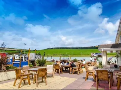 a patio with tables and chairs next to a river at 151 Newquay Bay Resort in Porth