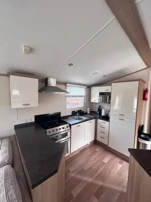 a kitchen with white cabinets and a black counter top at 151 Newquay Bay Resort in Porth