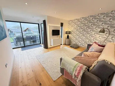 a living room with a couch and a large window at Fishers View, Castle Approach, Tregenna Castle in St Ives