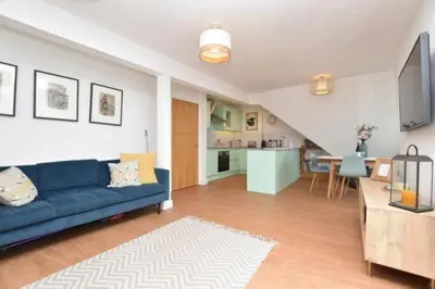 a living room with a blue couch and a kitchen at Penthouse Sea View Newquay Fistral Beach 3 Min Walk in Crantock