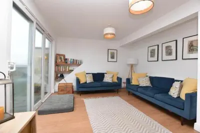 a living room with blue couches and a large window at Penthouse Sea View Newquay Fistral Beach 3 Min Walk in Crantock