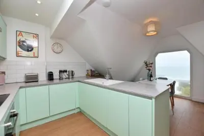 a kitchen with white cabinets and a sink and a window at Penthouse Sea View Newquay Fistral Beach 3 Min Walk in Crantock