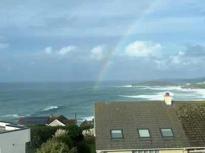 a rainbow in the sky over the ocean with houses at Penthouse Sea View Newquay Fistral Beach 3 Min Walk in Crantock