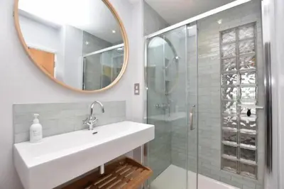 a bathroom with a sink and a mirror and a shower at Penthouse Sea View Newquay Fistral Beach 3 Min Walk in Crantock