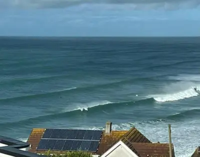 a view of the ocean with a house with solar panels at Penthouse Sea View Newquay Fistral Beach 3 Min Walk in Crantock